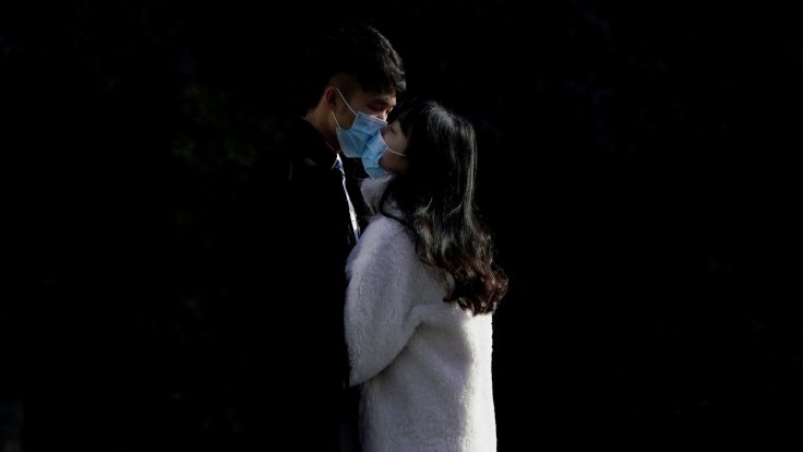 A couple wearing masks kiss at a main shopping area, in downtown Shanghai